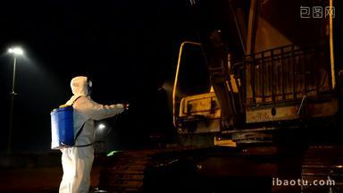 夜景防护服工作人员对挖掘机喷洒消毒灯光抗疫